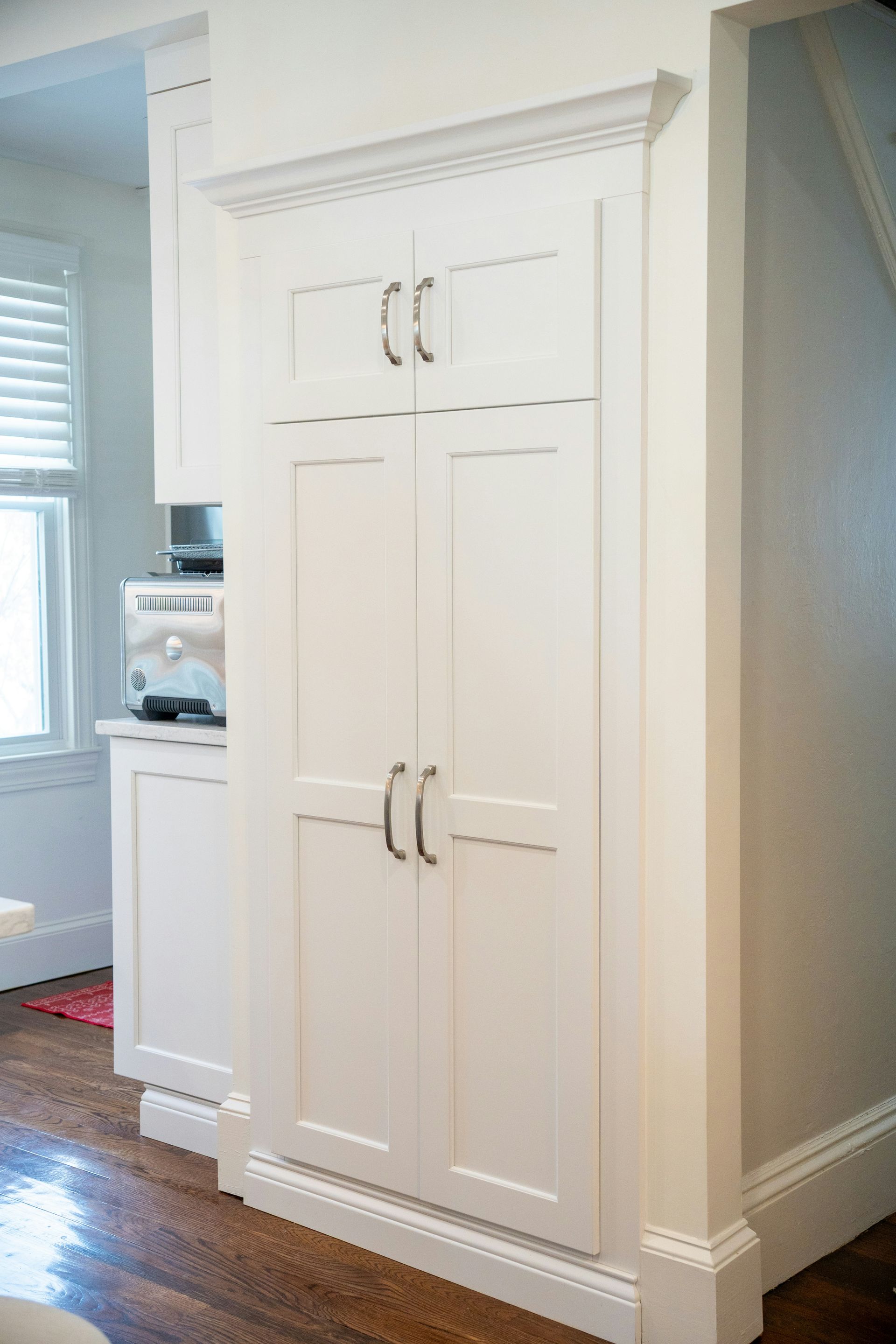 Tall white kitchen cabinets with silver handles in a bright home interior